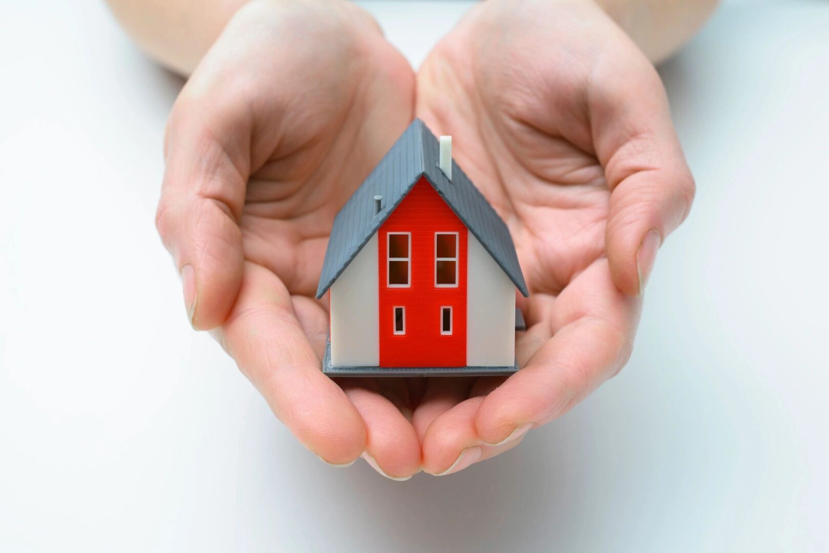 A person holding a small house in their hands.